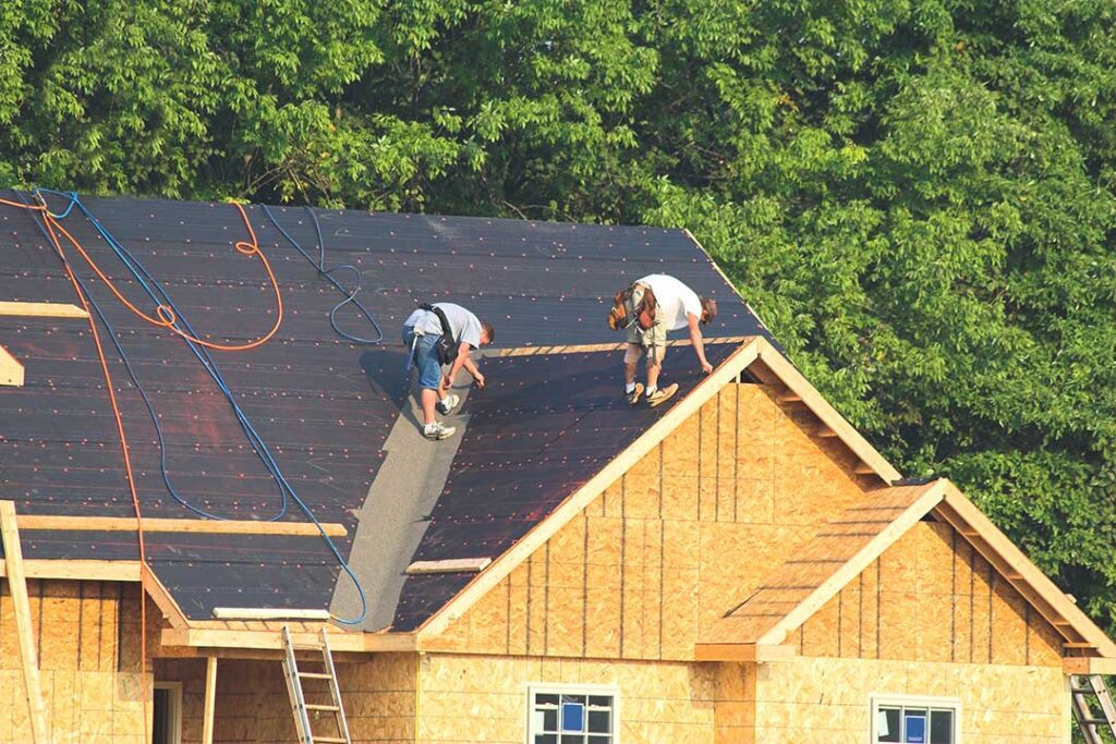 A homeowner compares a low flat roof and a pitched shingle roof on neighboring residential buildings after snowfall.